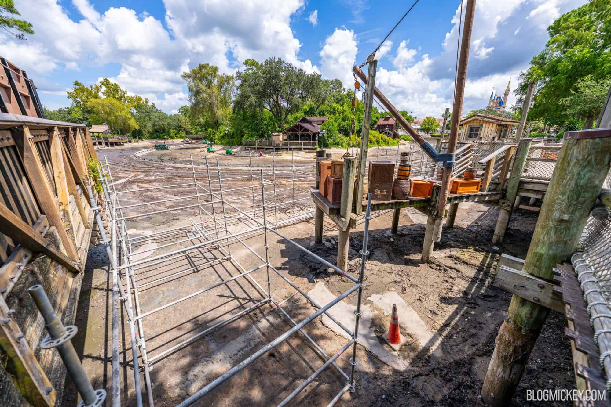 Drained Rivers of America riverbed with ongoing scaffolding constrcution near a wooden boardwalk
