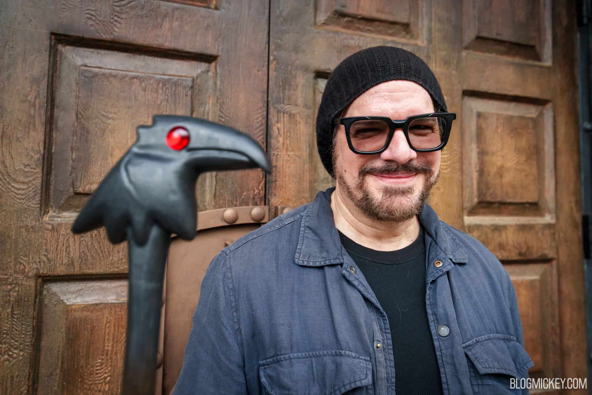 Man wearing black beanie and glasses holding a raven staff at Disney Springs.