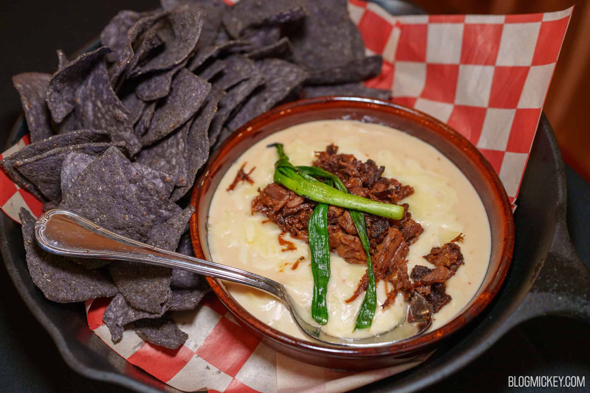 Creamy cheese dip topped with beef and green onions, served with blue corn chips.