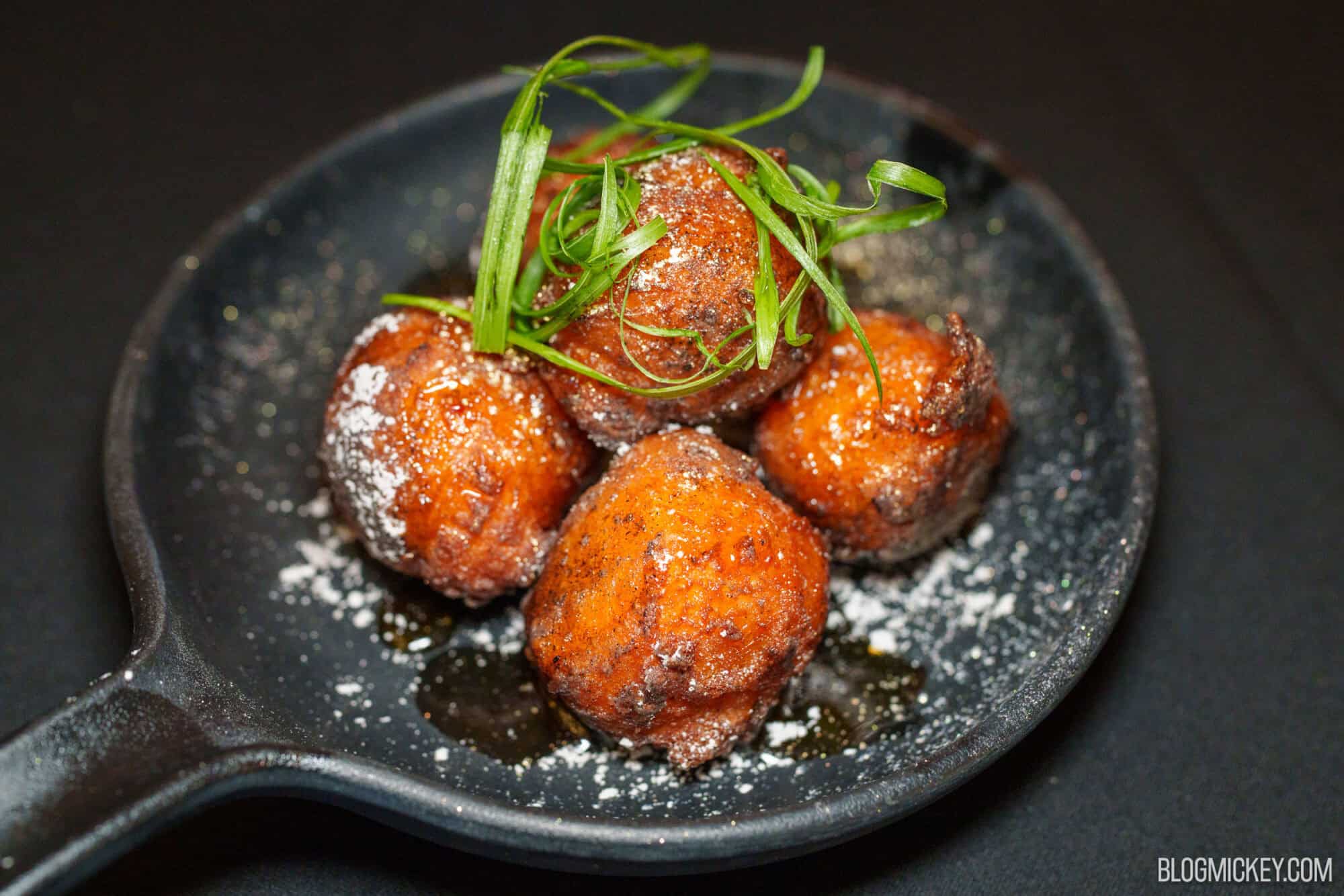 Fried appetizer balls garnished with green herbs at Magic Kingdom.