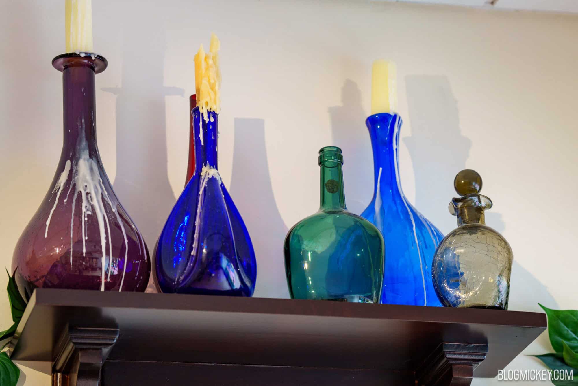 Colorful glass bottles in blue and green hues displayed on a mantel.
